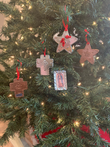 Five hand punched tin ornaments. one natural and one copper cross, one natural star with three chilis added, one copper star, and Our Lady of Guadalupe.